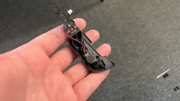 Close up view of the internal components of a high-end gaming mouse switch showing the metallic leaf spring and optical sensor path.