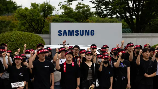 A busy Samsung semiconductor factory floor showing advanced robotic arms and cleanroom environments.