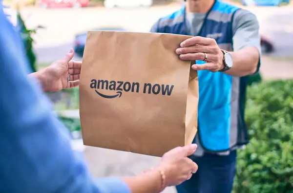A delivery driver carrying an Amazon package to a front door, representing the speed of the 30-minute delivery service.